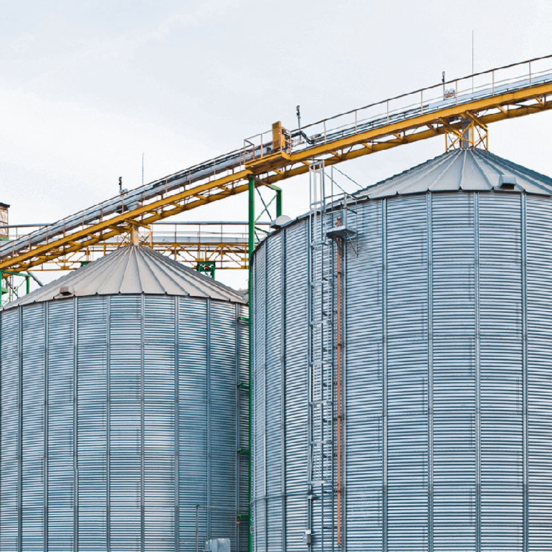 Grain silos stand against a blue sky.