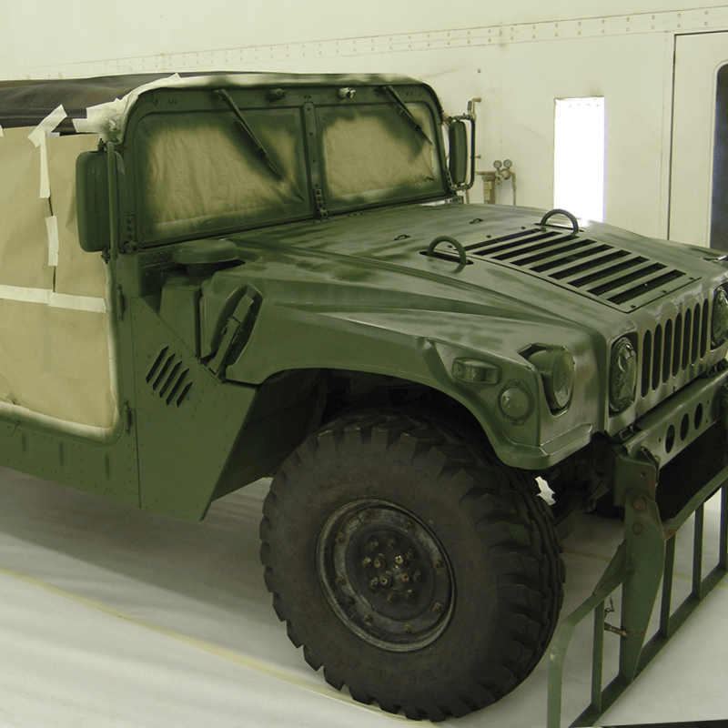 Military vehicle sits in paint spray booth