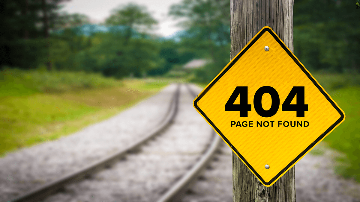 404 page not found yellow sign posted to wooden post stands before train tracks leading to distance