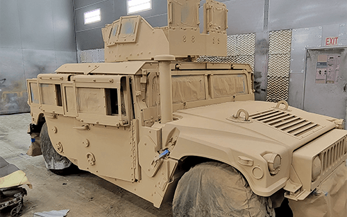 military vehicle prepped for painting sits in large indoor spray booth