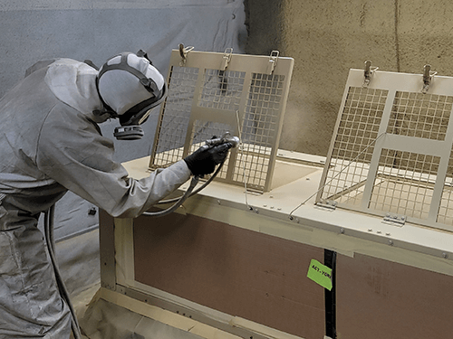 Painter trainee practices paint application on industrial part
