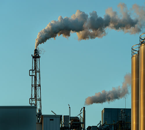 white smoke billowing into sky from a manufacturing smoke stack