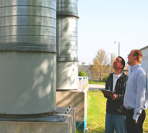 two men looking up at a grain bin during an environmental on-site visit