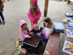 Three children with their hands in the vermicomposting pile observing the red worms