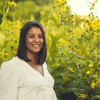 Molly Wells professional headshot in front of green and yellow prairie landscape