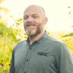 man in gray shirt outside yellow and green prairie background