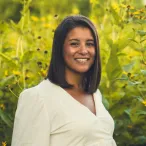 Molly Wells professional headshot in front of green and yellow prairie landscape