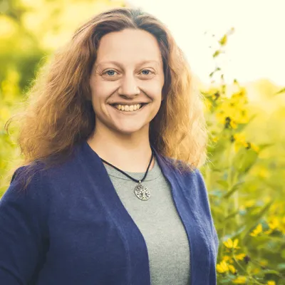 Link, Anastasia Bender standing before field of yellow flowers, profile page