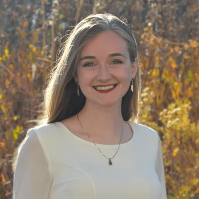 Student intern Paige German stands before field of fall prairie grass