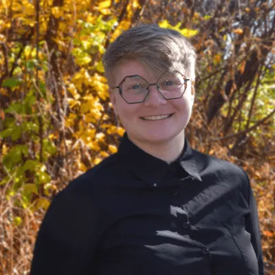 Student intern Nikayla Hoffmann stands before field of fall prairie grass