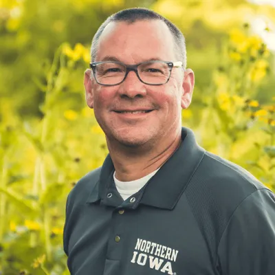 Dan Nickey standing before field of yellow flowers