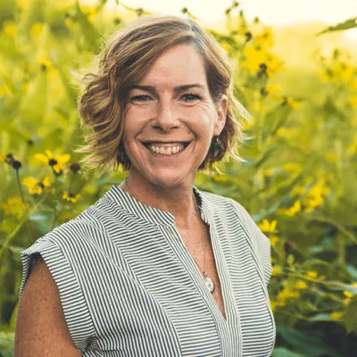 Link, Jennifer Trent standing before field of yellow flowers, profile page