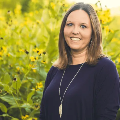 Link, Jennifer Wittenburg standing before field of yellow flowers, profile page